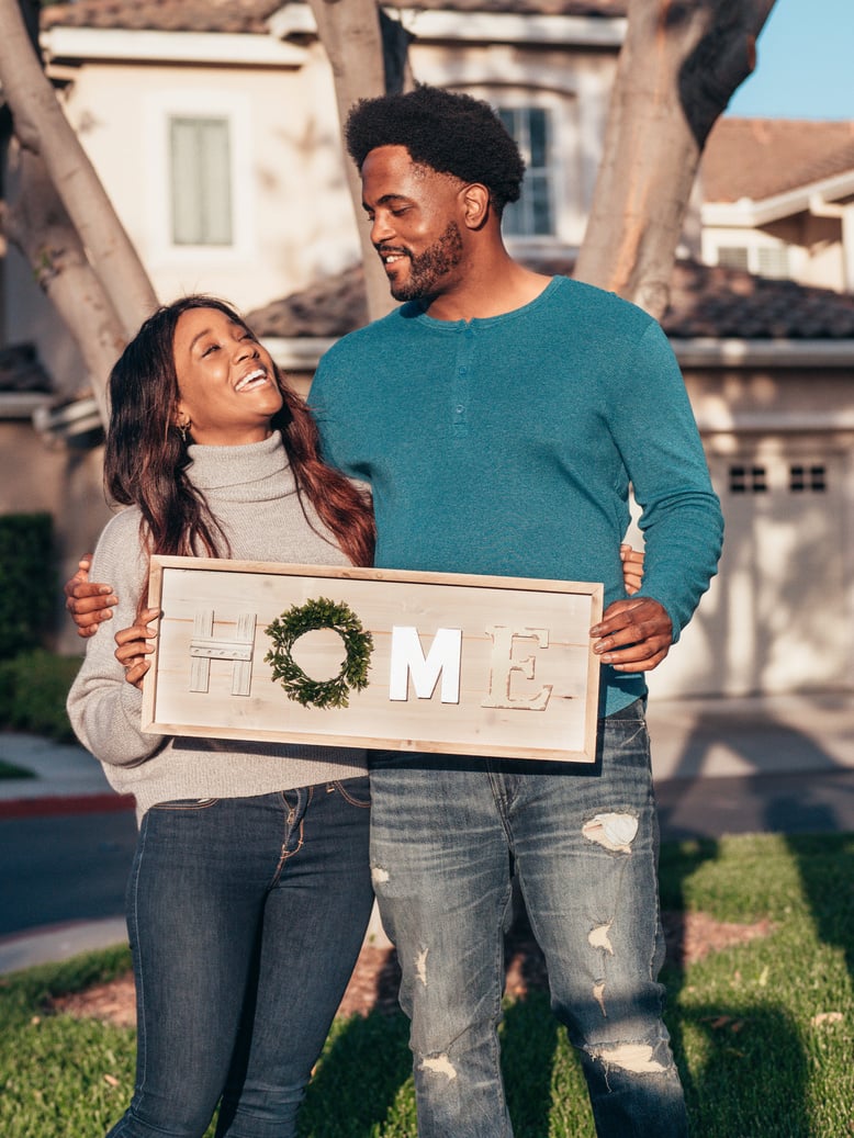 Man in Blue Sweater Holding a Wooden Home Decoration